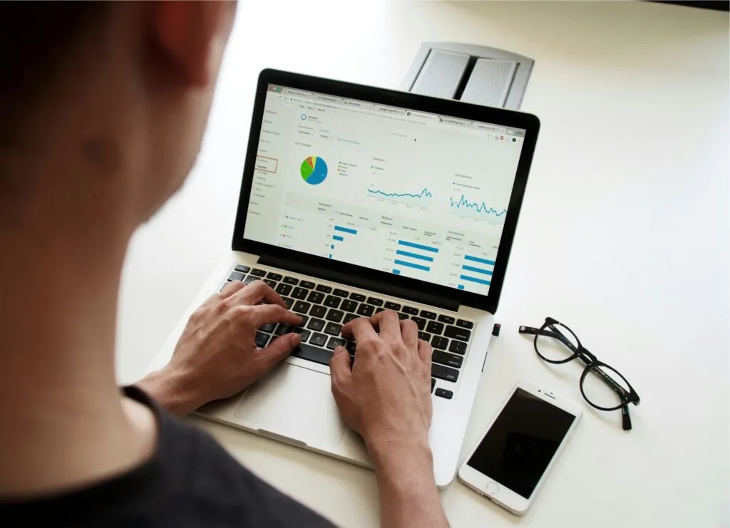 A young person with a laptop with pie chart showing 50/30/20 budgeting rule for needs, wants, and savings in personal finance.